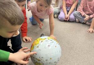 Dzieci z grupy Żabki szukają na zwykłym globusie Oceanu Arktycznego.