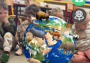 Dzieci z grupy Żabki obserwują Multiglobus po którym wędrują zwierzęta.