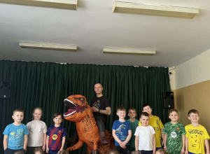 Grupowe zdjęcie dzieci z grupy Żabki z dinozaurem i Wujkiem Andrzejem.