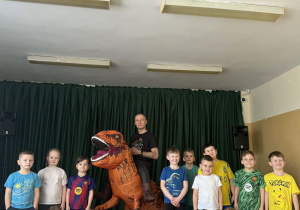 Grupowe zdjęcie dzieci z grupy Żabki z dinozaurem i Wujkiem Andrzejem.