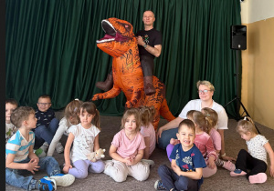 Grupowe zdjęcie dzieci z grupy Słoneczka z dinozaurem i Wujkiem Andrzejem.