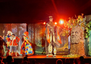 Aktorzy w barwnych strojach na scenie.