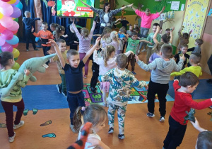 Przedszkolaki naśladują lot pterodaktyla podczas zabaw ruchowych.