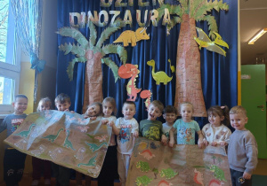 Zdjęcie grupowe grupy Szkraby na tle dekoracji tematycznej z plakatem "Park Jurajski".