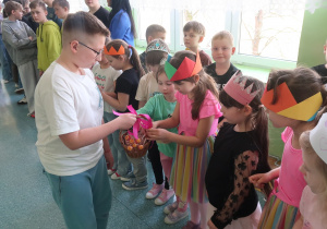 Chłopiec z klasy V częstuje dziewczynki smakołykami.