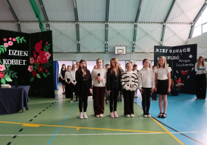 Uczennice klasy IV stoją na środku hali recytują wiersz pt. „ Pewność” Narcyzy Żmichowskiej.