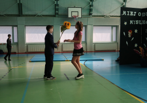 Prezentacja scenki przez uczniów klasy V podczas której chłopak wręcza słoneczniki dziewczynie.