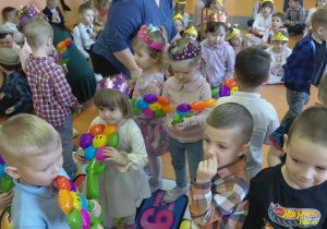 Chłopcy z grupy Kamyczki wręczają dziewczynką kolorowe kwiatki.