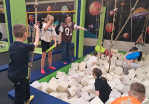 Uczniowie bawiący się na torze przeszkód, część uczniów bawi się w basenie z piankami.