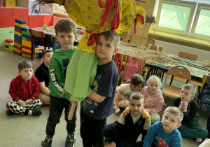 Dzieci niosą Marzannę w zielonej spódnicy i żółtej bluzce.