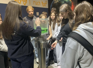 Grupa uczniów z zaciekawieniem patrzy na instruktaż edukatorki Experymentarium.