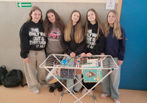 Uczennice klasy VII a prezentują swój kreatywny pomysł zastąpienia plecaków suszarką do wieszania prania.