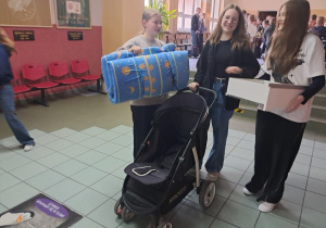 Uczennice klasy VII b oryginalnie świętują dzień bez plecaka, stoją na korytarzu i prezentują swoje zastępcze plecaki.