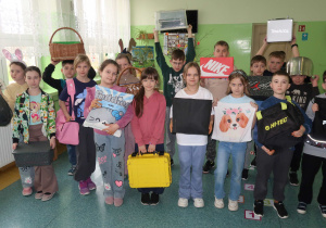 Uczniowie klasy trzeciej z nietypowymi przedmiotami zamiast plecaka.