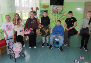 Uczniowie klasy czwartej prezentują pomysłowe zamienniki plecaków.