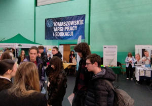 Uczniowie klas 8 na tle baneru Tomaszowskich Targów Pracy i Edukacji.