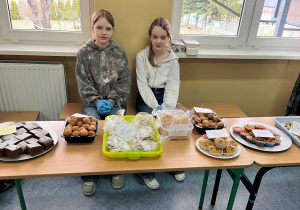 Stół ze słodkościami i uczennice klasy VI prowadzące sprzedaż.