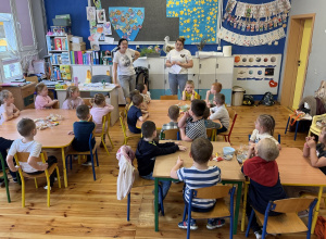 Pani Klaudia Wójciak przedstawia się dzieciom z grupy Promyczki, opowiada o swojej pasji do cukiernictwa, dzieci siedzą przy stolikach.