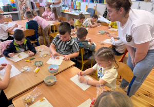 Pani Klaudia rozmawia z dziećmi dekorującymi kruche ciasteczka.