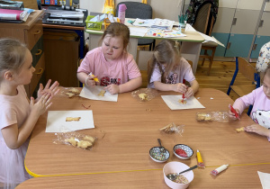 Dziewczynki z grupy Promyczki rozpoczynają dekorowanie ciasteczek przygotowanych przez panią Klaudię.