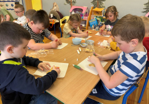 Dzieci z grupy Promyczki dekorują ciasteczka lukrowymi pisakami, tworząc kolorowe wzory.