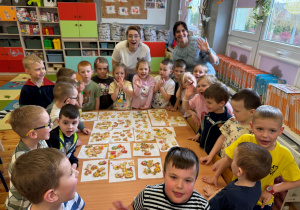 Zdjęcie grupowe dzieci z grupy Promyczki z panią Klaudią i wychowawca grupy, na stoliku prezentowane własnoręcznie dekorowane ciasteczka.