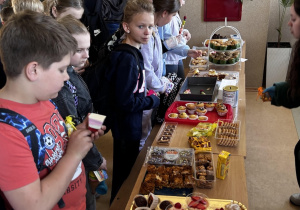 Uczniowie wybierają swoje smakołyki i pomagają.