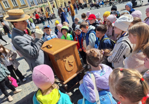 Dzieci spotykają na Rynku Starego Miasta Pana Kataryniarza.
