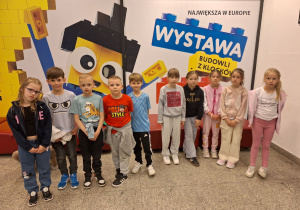 Grupa pierwszoklasistów przed wystawą z klocków Lego.