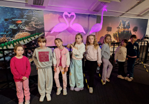 Dziewczynki stoją przed wystawą flamingów.