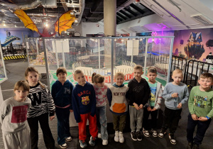 Chłopcy i dziewczynki stoją przed stadionem narodowym wybudowanym z lego.