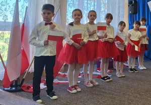 Uczniowie trzymają w ręku flagę Polski i śpiewają piosenkę o Polsce.