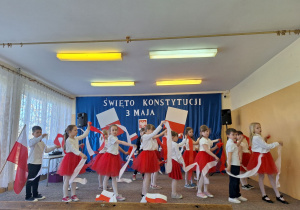 Pierwszoklasiści tańczą ze wstążkami przy muzyce.
