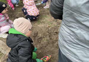 Dzieci przygotowują rabatę przed sadzeniem kwiatów i truskawek.