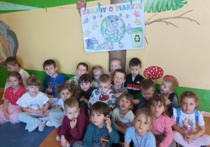 Zdjęcie grupowe dzieci z grupy Szkraby z własnoręcznie pokolorowanym plakatem "Dbamy o Planetę".