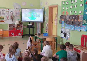 Dzieci z grupy Zuchy oglądają prezentację multimedialną o Dniu Ziemi.