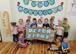 Zdjęcie grupowe dzieci z grupy Kamyczki z napisem DZIEŃ ZIEMI.